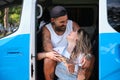 Young tattooed couple laugh and look each other sitting in the side of the van. Royalty Free Stock Photo