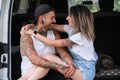 Young tattooed couple smile, hug and look each other in the back of the van. Royalty Free Stock Photo