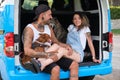 Young tattooed couple with their dogs smile and hug in the back of the van.