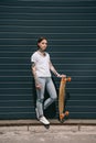 young tattooed woman standing with skateboard against