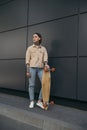 young tattooed woman standing with skateboard against black