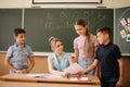 Young teacher check childrens work. Schoolboy and schoolgirl study