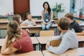 teacher in denim overalls sits on a bench and advises after-school workshops at school