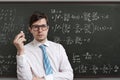 Young teacher in front of blackboard with math equations
