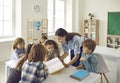 Happy young school teacher and group of elementary students reading book together Royalty Free Stock Photo