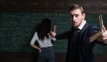 Young teacher holding a book in one hand and addressing his audience and with other one holding piece of chalk and Royalty Free Stock Photo