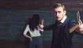 Young teacher holding a book in one hand and addressing his audience and with other one holding piece of chalk and Royalty Free Stock Photo