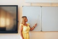 Young teacher holding a pointer in her hand and pointing to a white board, back to school, modern education Royalty Free Stock Photo