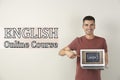 Young teacher with laptop on background. Online English course