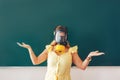 Young teacher in a medical mask holding a pointer in her hand and points to a white board, back to school, modern education, Royalty Free Stock Photo