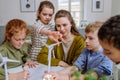 Young teacher with model of wind turbine learning pupils about wind energy. Royalty Free Stock Photo