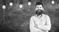 Young teacher near chalkboard in school classroom. Man with beard and mustache on smiling face stand in front of Royalty Free Stock Photo