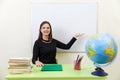 Young teacher sitting at a table near empty white board in classroom Royalty Free Stock Photo