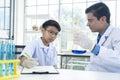 Young teacher and student boy use microscope in science class at laboratory Royalty Free Stock Photo