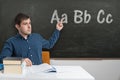 Young teacher is teaching ABC at elementary school. Letters written on blackboard Royalty Free Stock Photo