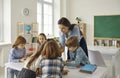 Young teacher teaching schoolchildren or preschooler group in classroom Royalty Free Stock Photo