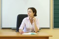 Young teacher in white shirt sits at table with