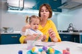 Young teacher woman and cute little girl are painting Easter eggs at the kindergarten. Concept of preschool education
