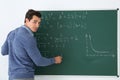Young teacher writing math formulas on chalkboard Royalty Free Stock Photo