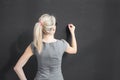 Young teacher writing with white chalk on empty blackboard in classroom Royalty Free Stock Photo