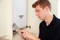 Young technician servicing a boiler, using tablet computer