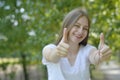 Young teen age girl showing happy thumbs up gesture with hand. Approving expression looking at the camera. Summer, green Royalty Free Stock Photo