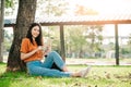 A young or teen asian girl student in university smiling and reading the book and look at the tablet Royalty Free Stock Photo