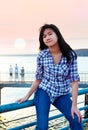 Young teen biracial Asian girl sitting on metal railing by lake Royalty Free Stock Photo