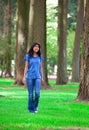 Young teen biracial girl walking under tall trees