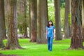 Young teen biracial girl walking under tall trees