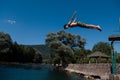 Young teen boy jumping flying and diving in the river. Clear blue sky and trees in distance as a natural background. Royalty Free Stock Photo