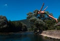 Young teen boy jumping flying and diving in the river. Clear blue sky and trees in distance as a natural background. Royalty Free Stock Photo