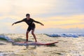 Young teen boy surfer riding waves on soft board in Rayong beach, Thailand. Rookie teenager surfboard student playing on water in Royalty Free Stock Photo