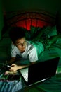 Young Teen in front of a laptop computer and on a bed Royalty Free Stock Photo