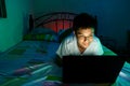 Young Teen in front of a laptop computer and on a bed Royalty Free Stock Photo