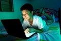 Young Teen in front of a laptop computer and on a bed Royalty Free Stock Photo