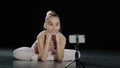 Young teen girl child teenager ballerina gymnast dancer sitting on floor recording vlog waving hello to mobile phone Royalty Free Stock Photo