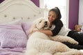 Young teen girl cuddling pet dog on her bed Royalty Free Stock Photo