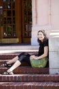 Young teen girl enjoying sunshine, sitting on brick steps outdoors