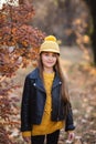 Young teen girl with long blond hair in yellow sweater, hat and leather jacket posing in the autumn park. Copy space Royalty Free Stock Photo