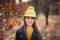 Young teen girl with long blond hair in yellow sweater, hat and leather jacket posing in the autumn park. Copy space Royalty Free Stock Photo