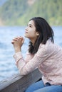 Young teen girl praying quietly on lake pier