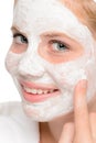 Young teen girl putting facial mask cream