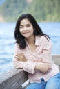 Young teen girl sitting quietly on lake pier