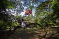 Young teen girl sitting on tree and holding balloons in hand.