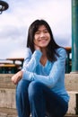 Young teen girl sitting on wooden steps outdoors on overcast cloudy day