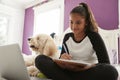 Young teen girl studying on her bed beside pet dog Royalty Free Stock Photo