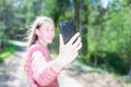 Young teen girl traveler taking selfie on mobile phone in a summer day forest. girl looking at smartphone camera Royalty Free Stock Photo