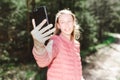 Young teen girl traveler taking selfie on mobile phone in a summer day forest. girl looking at smartphone camera Royalty Free Stock Photo