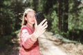 Young teen girl traveler taking selfie on mobile phone in a summer day forest. girl looking at smartphone camera Royalty Free Stock Photo